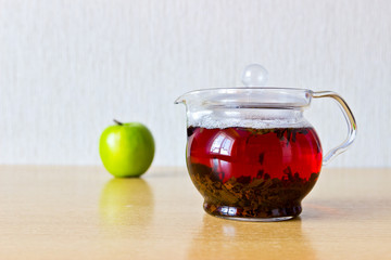 Strong black ceylon tea in glass teapot and fresh ripe apple