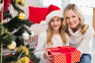 Festive mother and daughter beside christmas tree