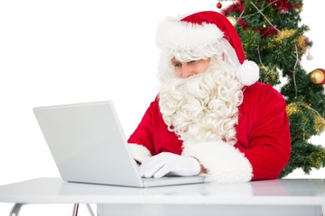 Father christmas using his laptop near christmas tree