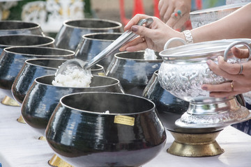 Fototapeta na wymiar puts food offerings in a Buddhist monk's alms bowl