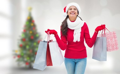 Composite image of festive brunette holding shopping bags