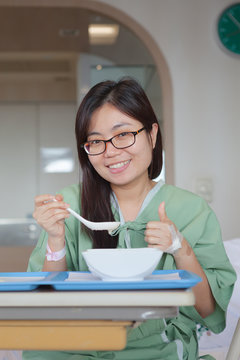 Asian girl patient Enjoying Meal In Hospital Bed