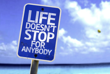Life Doesn't Stop for Anybody sign with a beach on background
