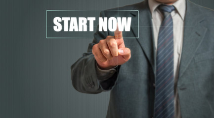 Business Man Choosing "Start Now" Over Grey Background