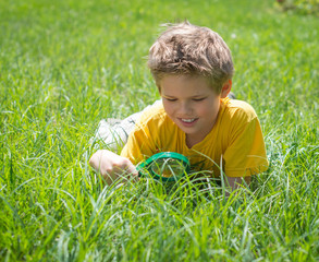 Kid with magnifying glass outdoors.