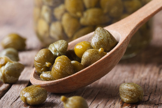 ripe capers in a wooden spoon closeup on a background of a jar