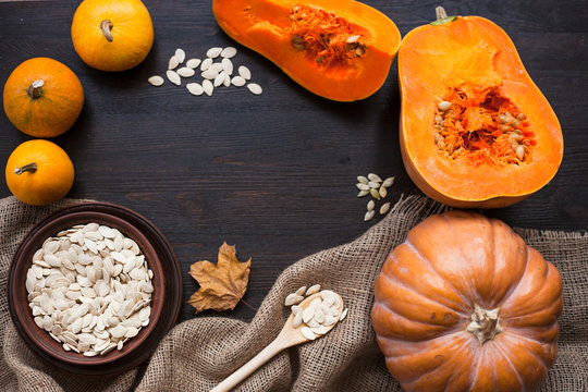 Pumpkins and a bowl with toasted pumpkin seeds, wooden spoon
