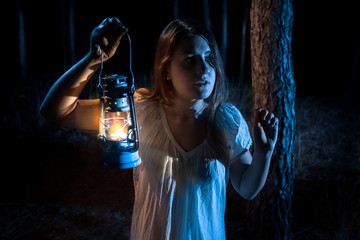 portrait ofnwoman lost in forest lighting the way with lantern