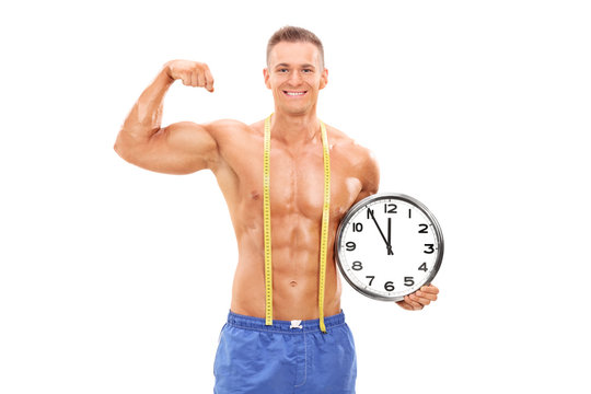 Handsome male athlete holding a big wall clock  background