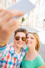 smiling couple with smartphone in city