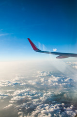 Fototapeta premium Wing of an airplane flying above the clouds