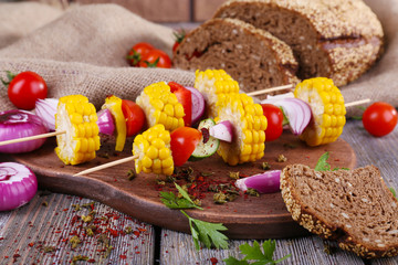 Sliced vegetables on wooden picks and bread on table close-up