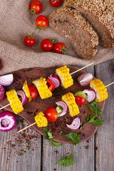 Sliced vegetables on wooden picks and bread on table close-up