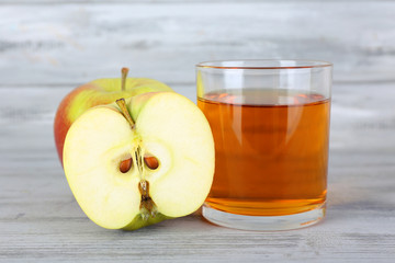 glass of apple juice and fresh apples on grey wooden table