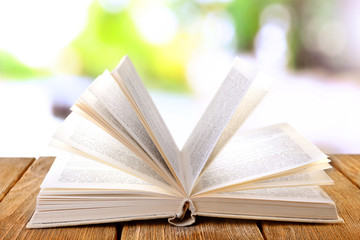 Open book on wooden table on natural background