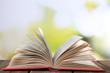 Open book on wooden table on natural background