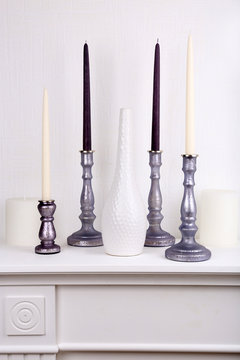 Candles in candle holders and vase on table on light background