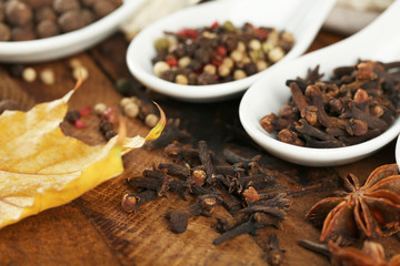 Different spices in spoons with yellow leaves