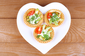 Tartlets with greens and vegetables with sauce on plate on