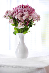 Beautiful flowers in vase on light background