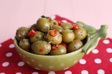 Green olives in oil with spices and rosemary in bowl