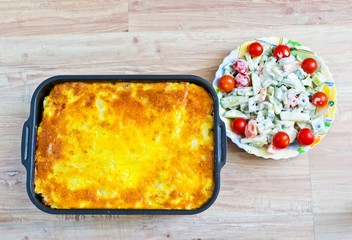 Potato casserole with eggs and meat. Fresh vegetable salad