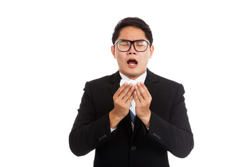 Asian businessman caught cold. Sneezing into tissue.