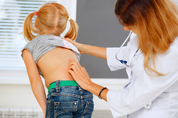 Pediatrician examining little girl with back problems. - obrazy, fototapety, plakaty