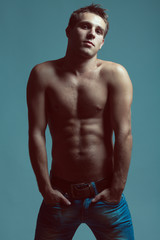 Fototapeta premium Blue jeans concept. Handsome muscular male model with nice abs