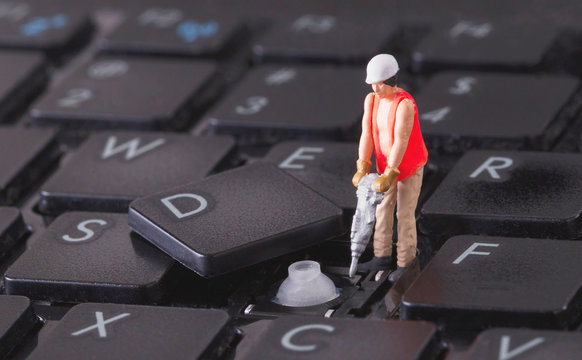 Miniature worker with drill working on keyboard