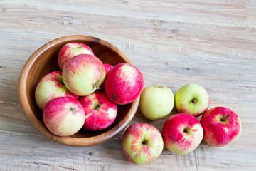 Fototapeta na wymiar Fresh ripe apples in wooden bowl on wooden background