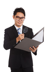 Asian businessman with  magnifying glass check data in folder