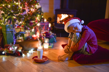 Obraz premium A little boy fell asleep while waiting for Santa Claus in front