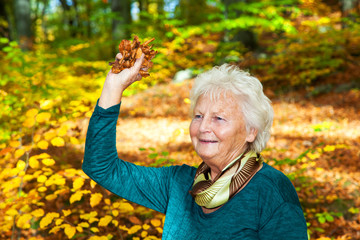 Senior woman poses with autumn leaves in the park