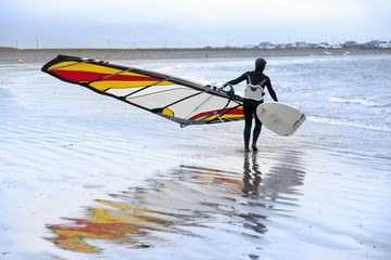 Naklejka premium lone windsurfer getting ready to surf
