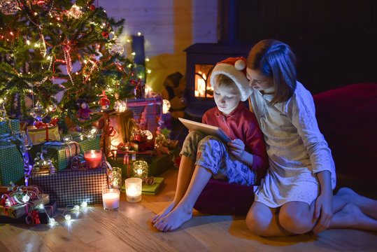 Christmastime, two kids in pajamas having fun on a digital table
