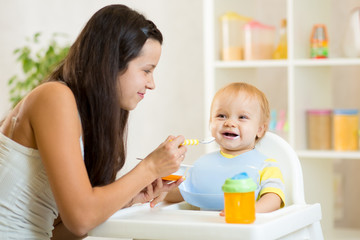 Obraz na płótnie Canvas Mother spoon feeding her kid