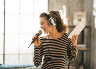 Happy young woman singing karaoke in loft apartment