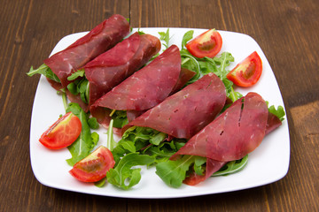 Rolls of dried beef on plate over wooden table