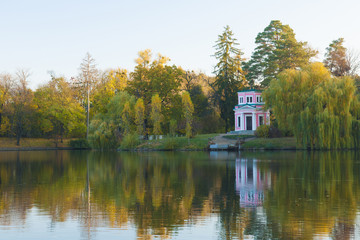 Fototapeta na wymiar Ancient pink pavilion on autumn park lake