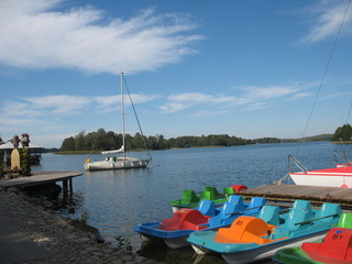 Fototapeta na wymiar Яркие лодки и водные велосипеды для отдыха на озере