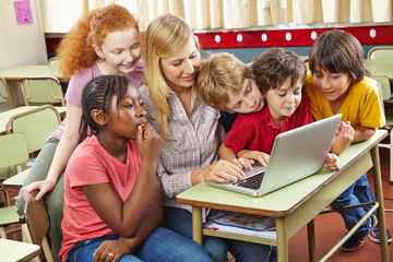 Kinder am Laptop mit Lehrer in Schule