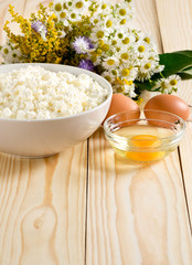 Fototapeta na wymiar Cottage cheese and eggs on the meadow flowers background