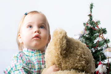 Cute little girl looking up and holding a teddy bear near  the C