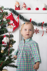 Cute surprised little girl stands near  the Christmas tree