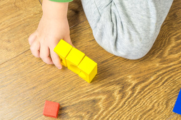 child is playing with multicolored cubes on wooden floor