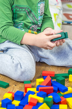 child is playing with multicolored cubes on wooden floor