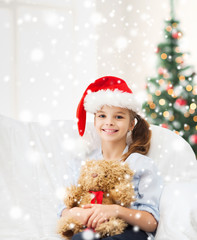 smiling girl in santa helper hat with teddy bear