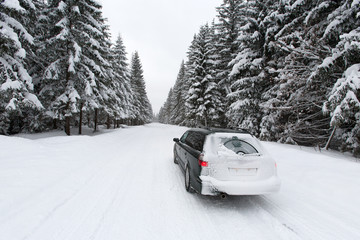 snow covered car on the winter road in forest 2