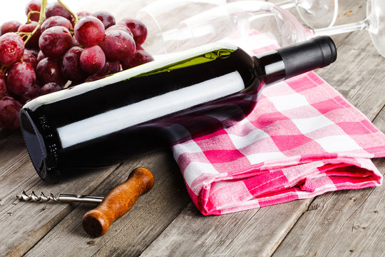 bottle of wine corkscrew amd grapes on wooden table